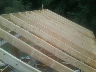 New roof rafters set over an addition before sheathing in Byron